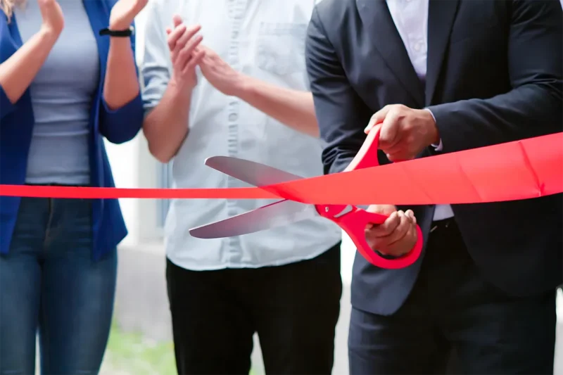 A group of people cutting a ribbon with scissors.