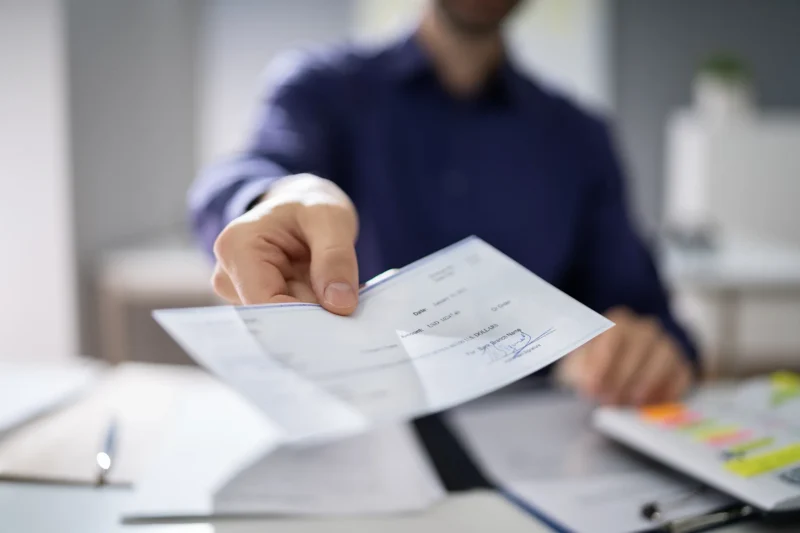A man hands a check across a table.