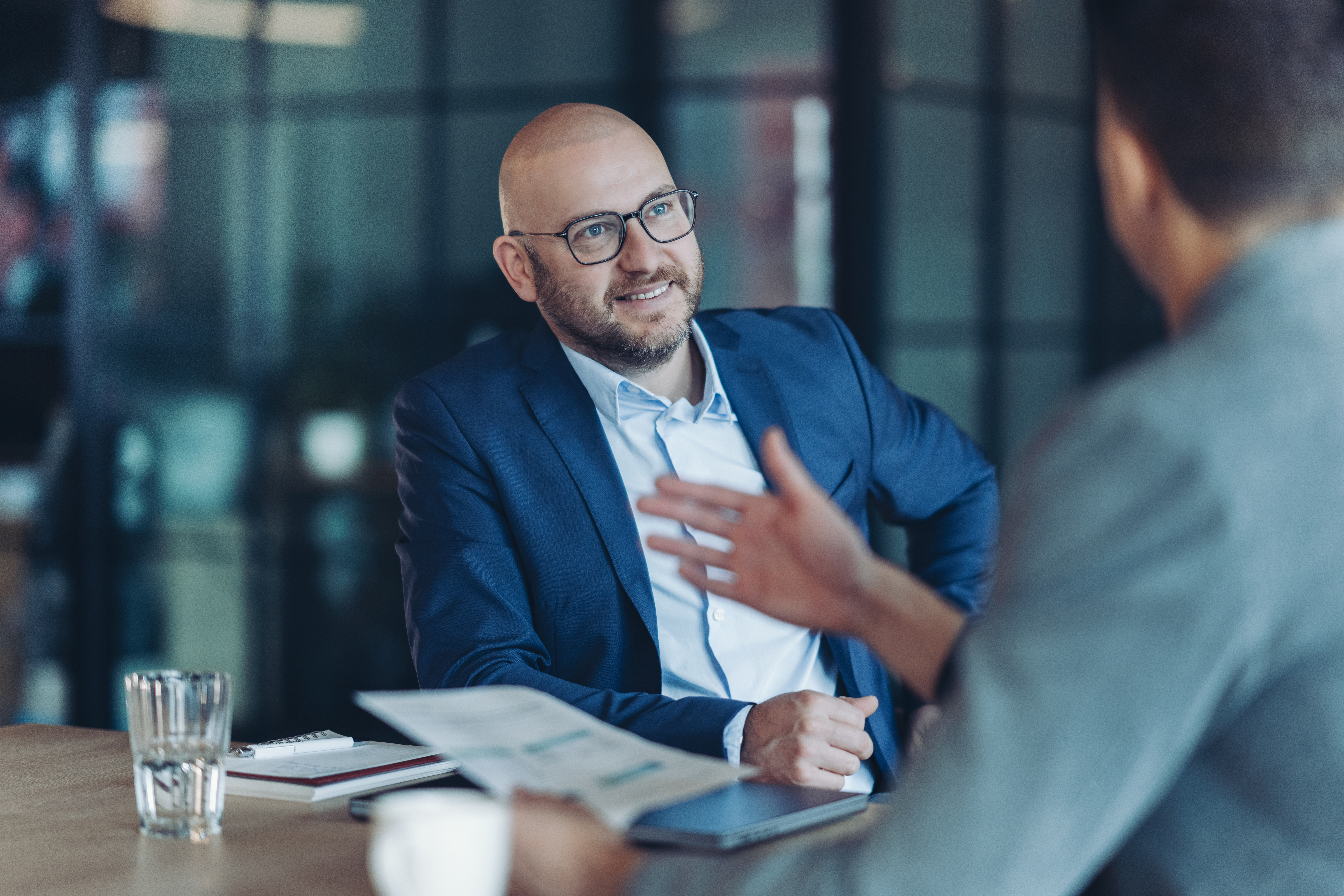 A banker in a blue suit discussing jumbo money market account options with a client at a conference table